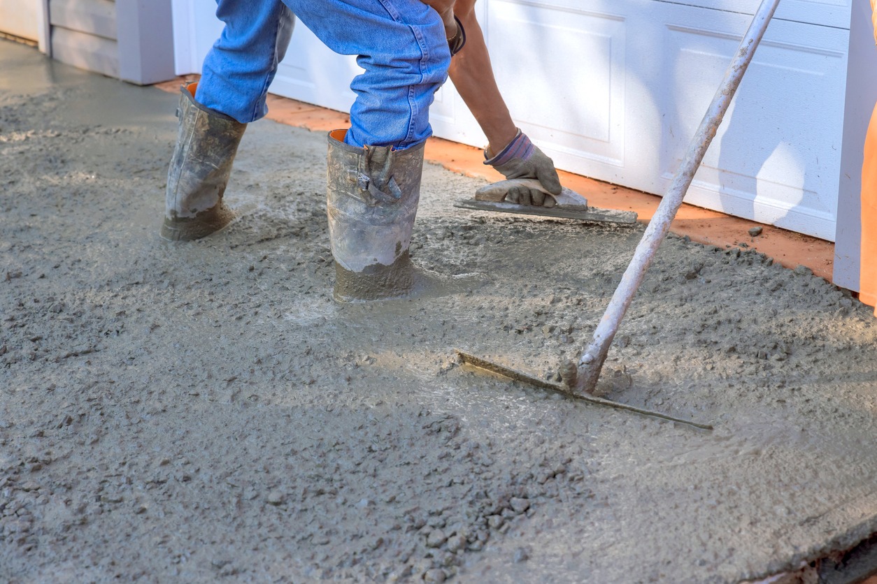 Concrete leveling workers on construction site with a mix trowel leveling to concrete driveway