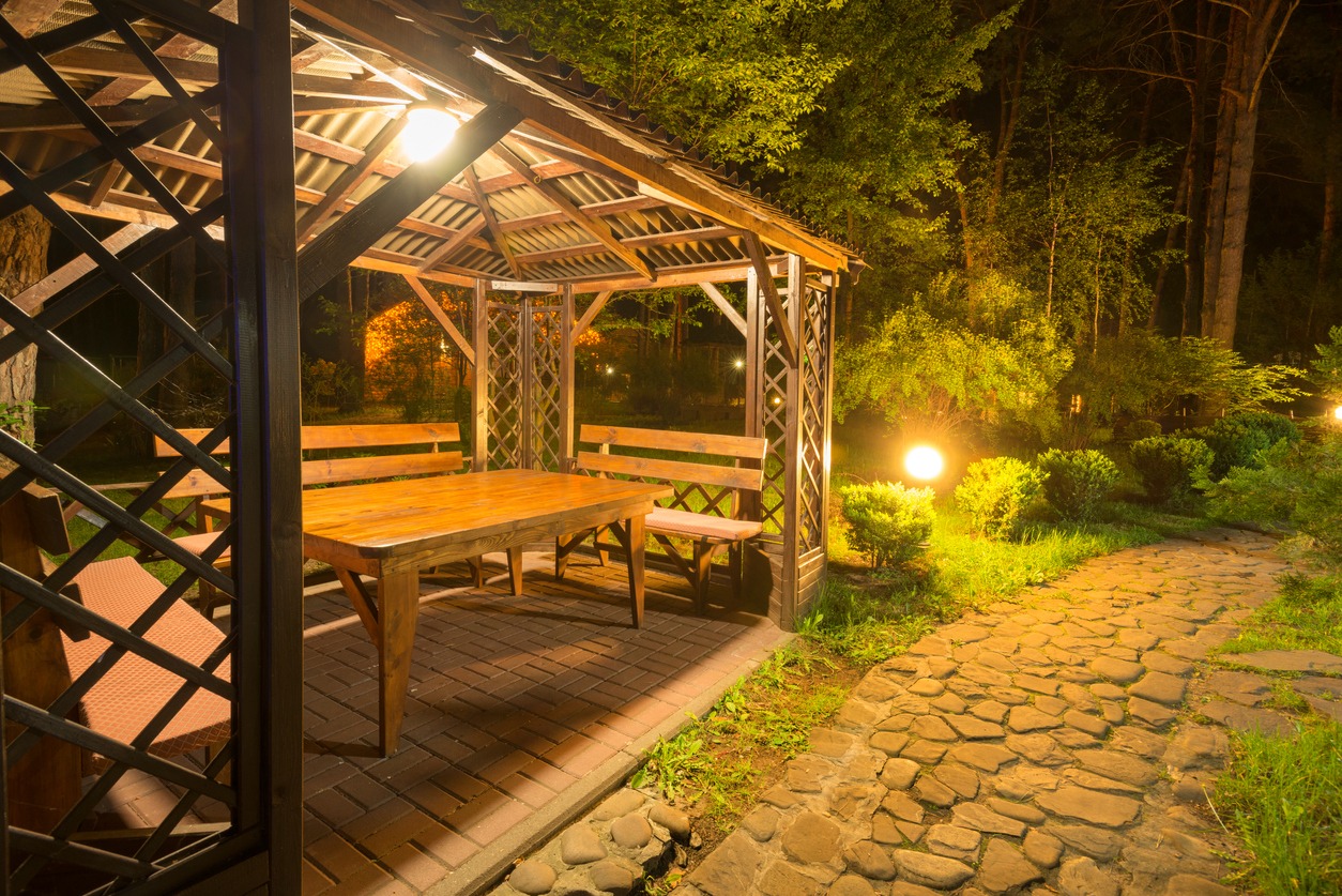 Stone path to the lighted cozy wooden patio gazebo in the backyard