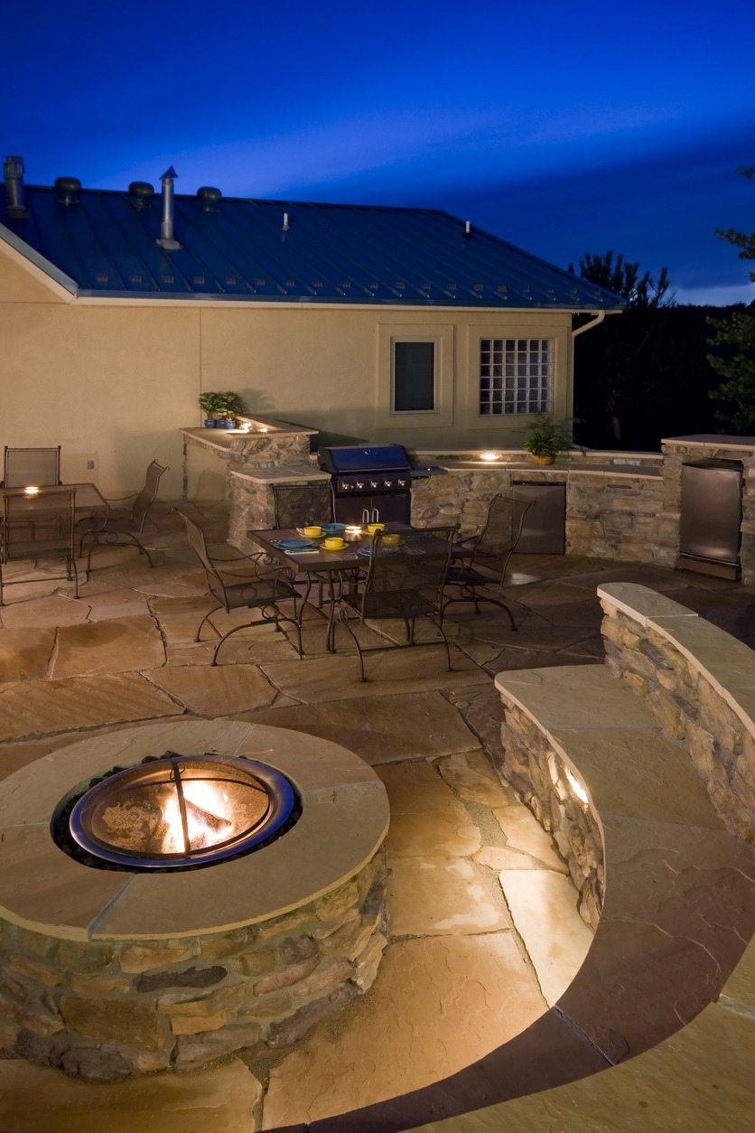 beautiful backyard at dusk with lighting for a fire pit, outdoor kitchen and seating